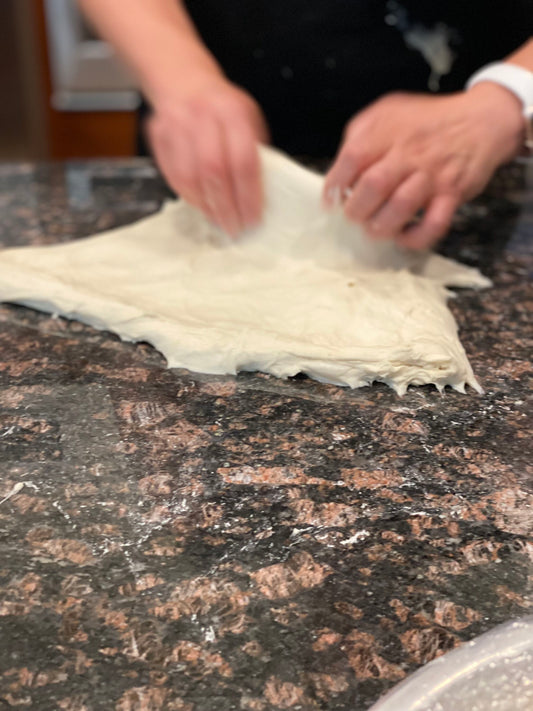 Hands stretching soft sourdough dough
