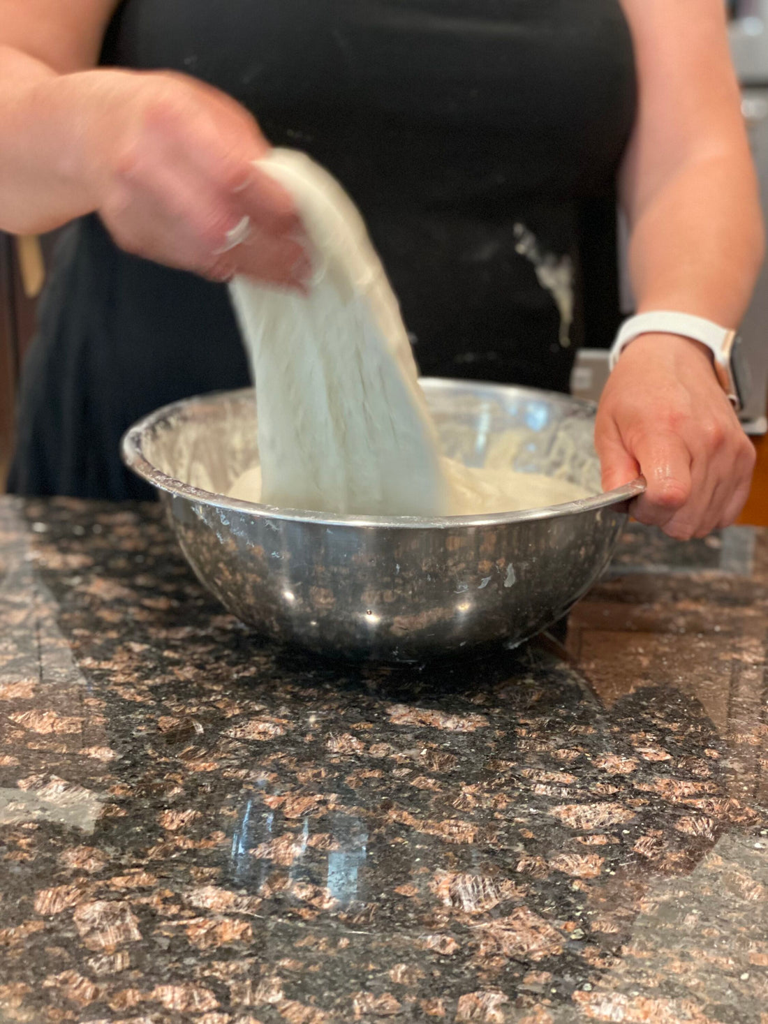 A healthy, elastic sourdough starter stretching from a bowl